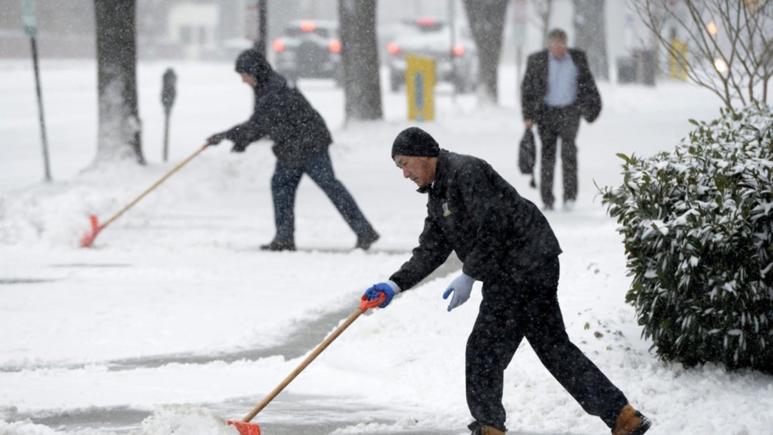 Dos hombres limpian una acera durante una tormenta invernal de nieve en Washington, EEUU. Imagen de archivo. EFE/Michael Reynolds