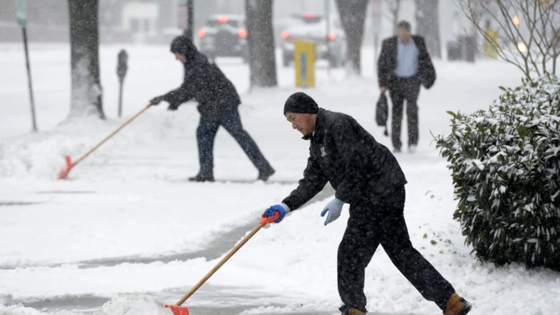 Dos hombres limpian una acera durante una tormenta invernal de nieve en Washington, EEUU. Imagen de archivo. EFE/Michael Reynolds